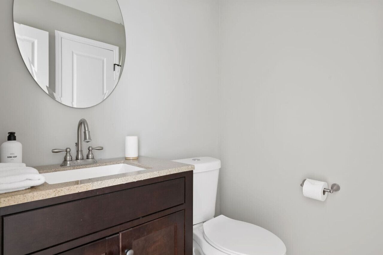 Une salle de bain équipée d’un lavabo, d’un miroir, de toilettes et d’un porte-serviettes.