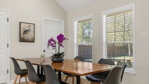 A dining area with a wooden table, six black chairs, and a potted orchid. - Augusta: 1 Mile from Texas A&M/Near Sorority Row (College Station)