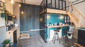 A modern kitchen with a bar area, wooden stools, and a staircase. - Unique & stylish Loft Style Studio with Terrace, Parking & close to the beach (Stoke Fleming)