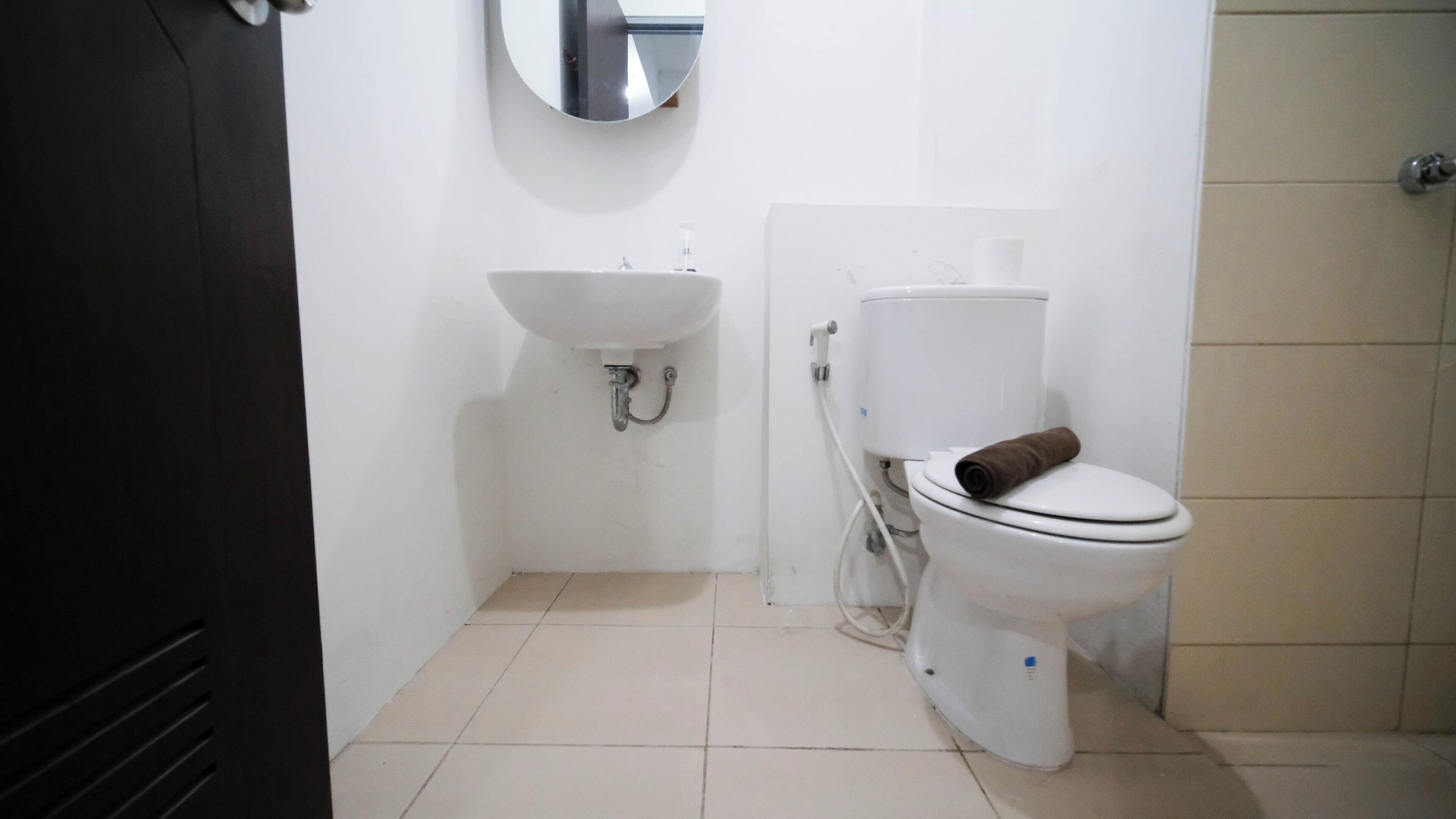 A small, clean bathroom with a white sink, toilet, and a mirror above the sink.