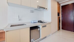 A modern kitchen with a built-in dishwasher, a stainless steel sink, and a microwave. - Well Furnished And Nice Studio Sky House Bsd Apartment (Pagedangan)
