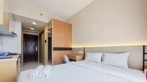 A hotel room with a bed, a desk, and a kitchenette. - Well Furnished And Nice Studio Sky House Bsd Apartment (Pagedangan)