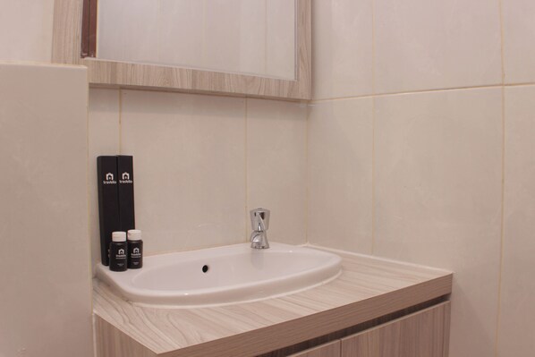 A bathroom with a white sink, a mirror above it, and two toiletries on the counter. - Fancy And Nice Studio At Grand Kamala Lagoon Apartment (Bekasi)