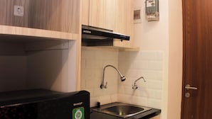 Una cucina compatta con un piano di lavoro nero, un lavello in acciaio inossidabile e pensili in legno.