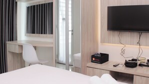 Una camera d'albergo con un letto, una scrivania, una sedia, una televisione e un frigobar.