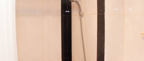 A shower area with a handheld showerhead and a wall-mounted control panel.