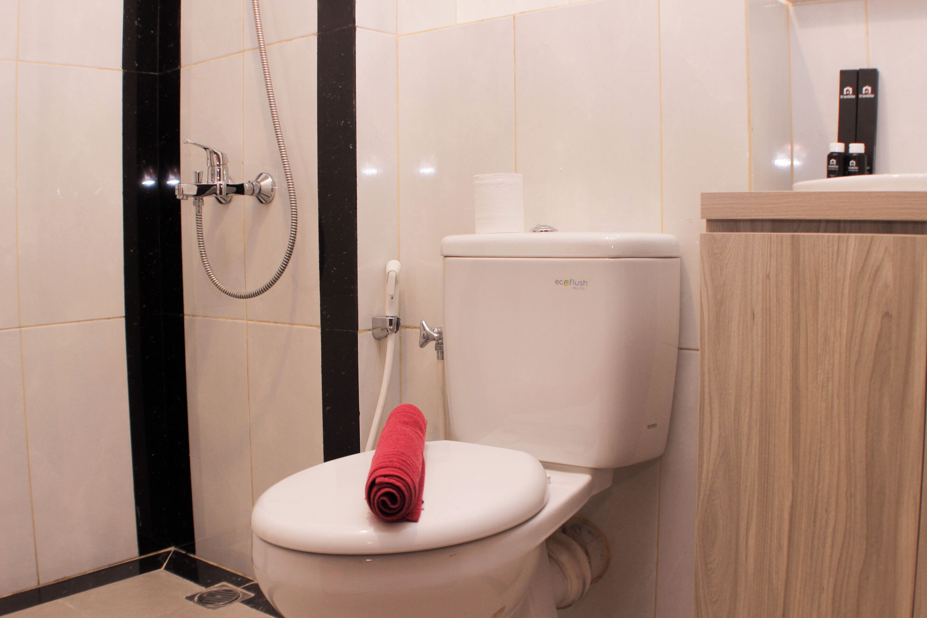 A bathroom with a white toilet, a shower, and a wooden cabinet.