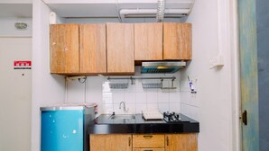 Une cuisine de taille réduite avec des meubles en bois, un plan de travail noir et un réfrigérateur bleu.