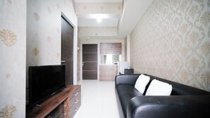 Uma sala de estar moderna com uma televisão de tela plana, um sofá de couro preto e um móvel para entretenimento de madeira.