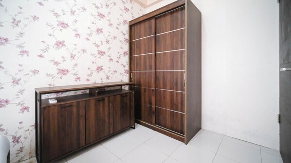 A corner room with a wardrobe, a small cabinet, and floral wallpaper. - Tidy And Comfy 1Br At Tamansari Prospero Sidoarjo Apartment (Sidoarjo)