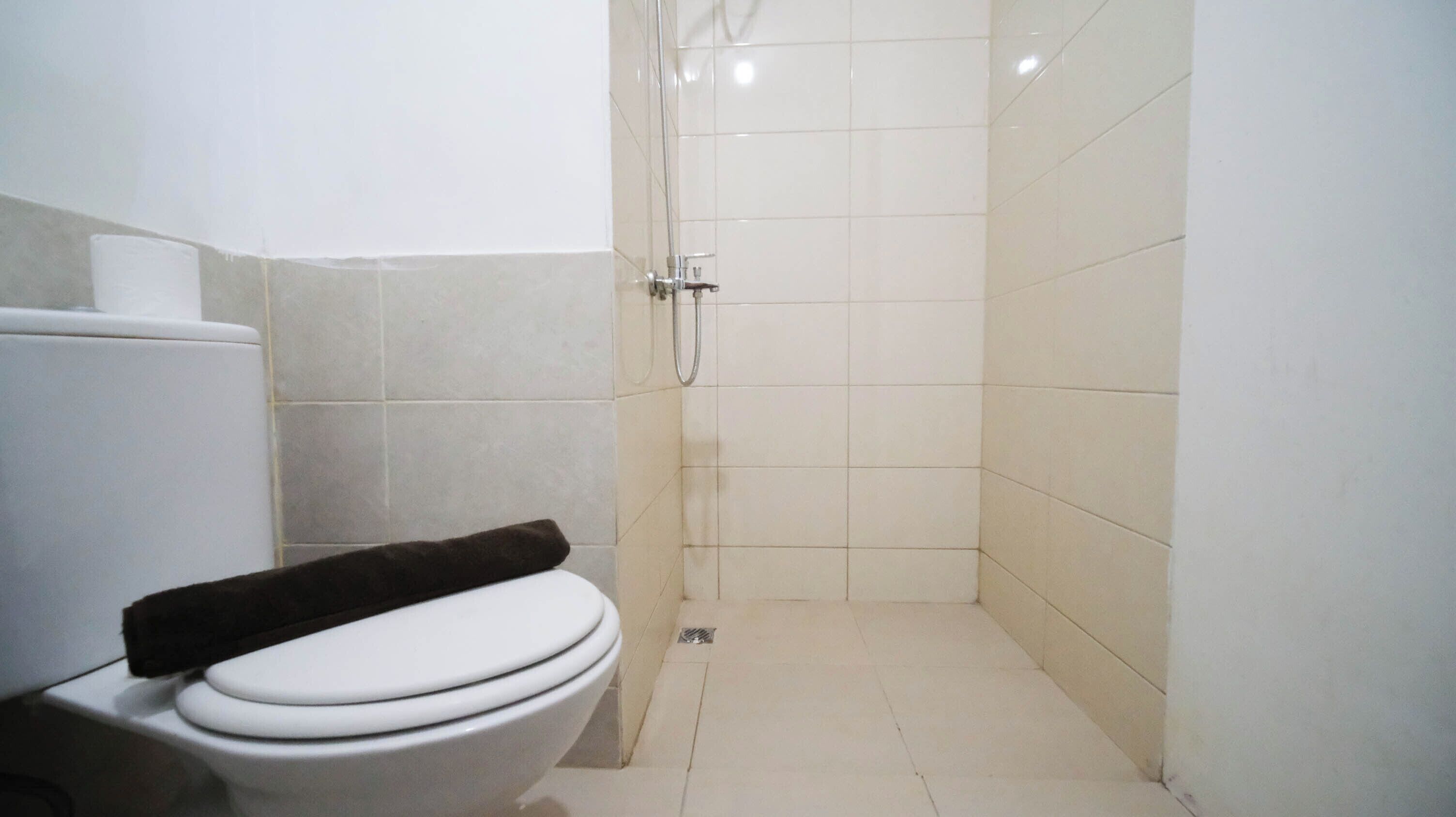Un baño pequeño y funcional con inodoro, cabina de ducha y paredes de azulejos.