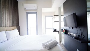 Ein Hotelzimmer mit einem Bett, einem flachbildfernseher an der Wand und einem Fenster mit Blick nach draußen.