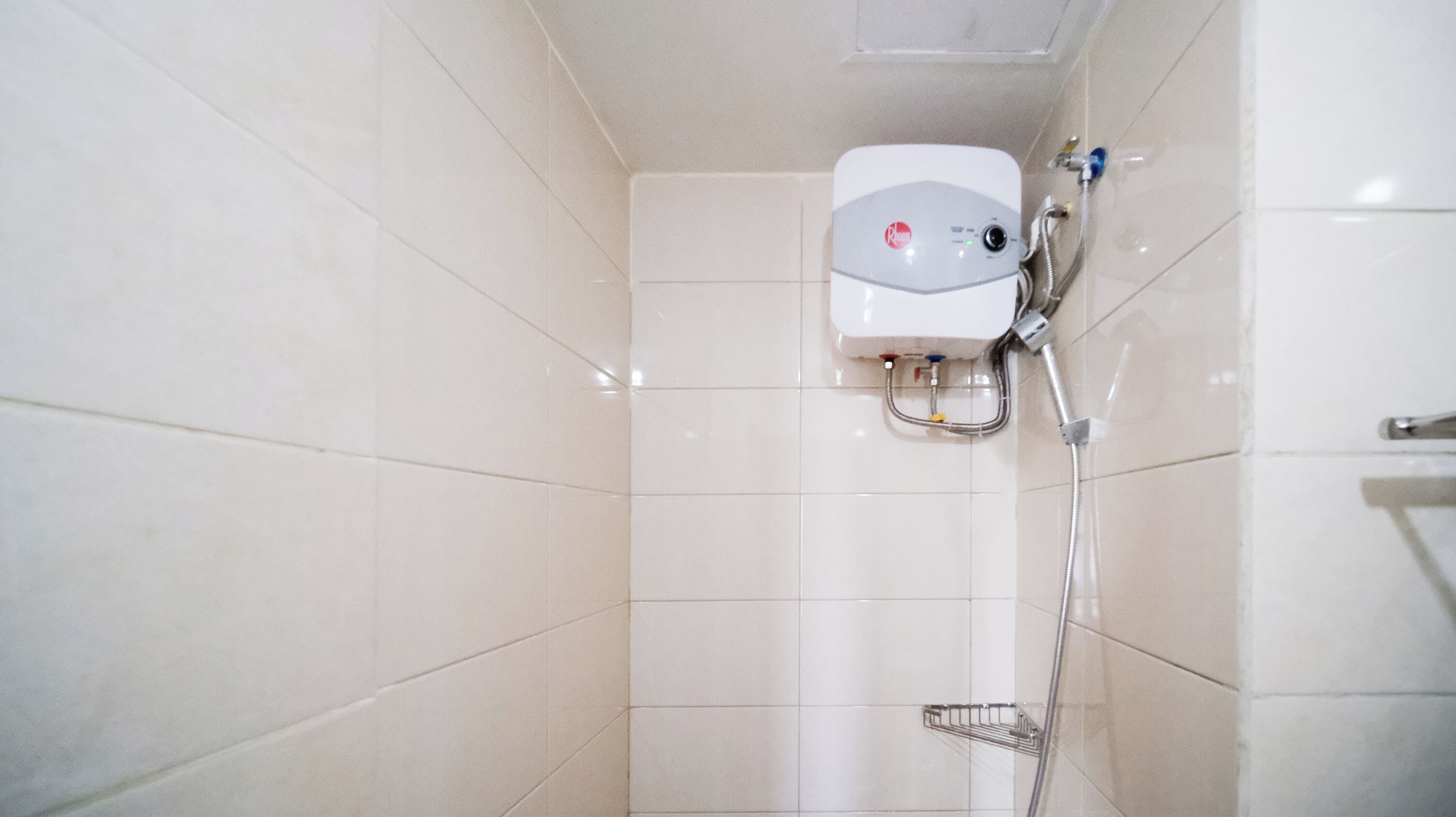 Un pequeño cuarto de baño con azulejos, con cabezal y panel de control de ducha blancos.