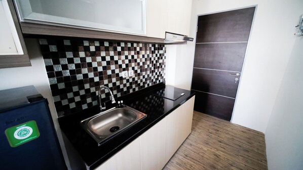 A modern kitchen with a black countertop, a stainless steel sink, and a checkered backsplash.