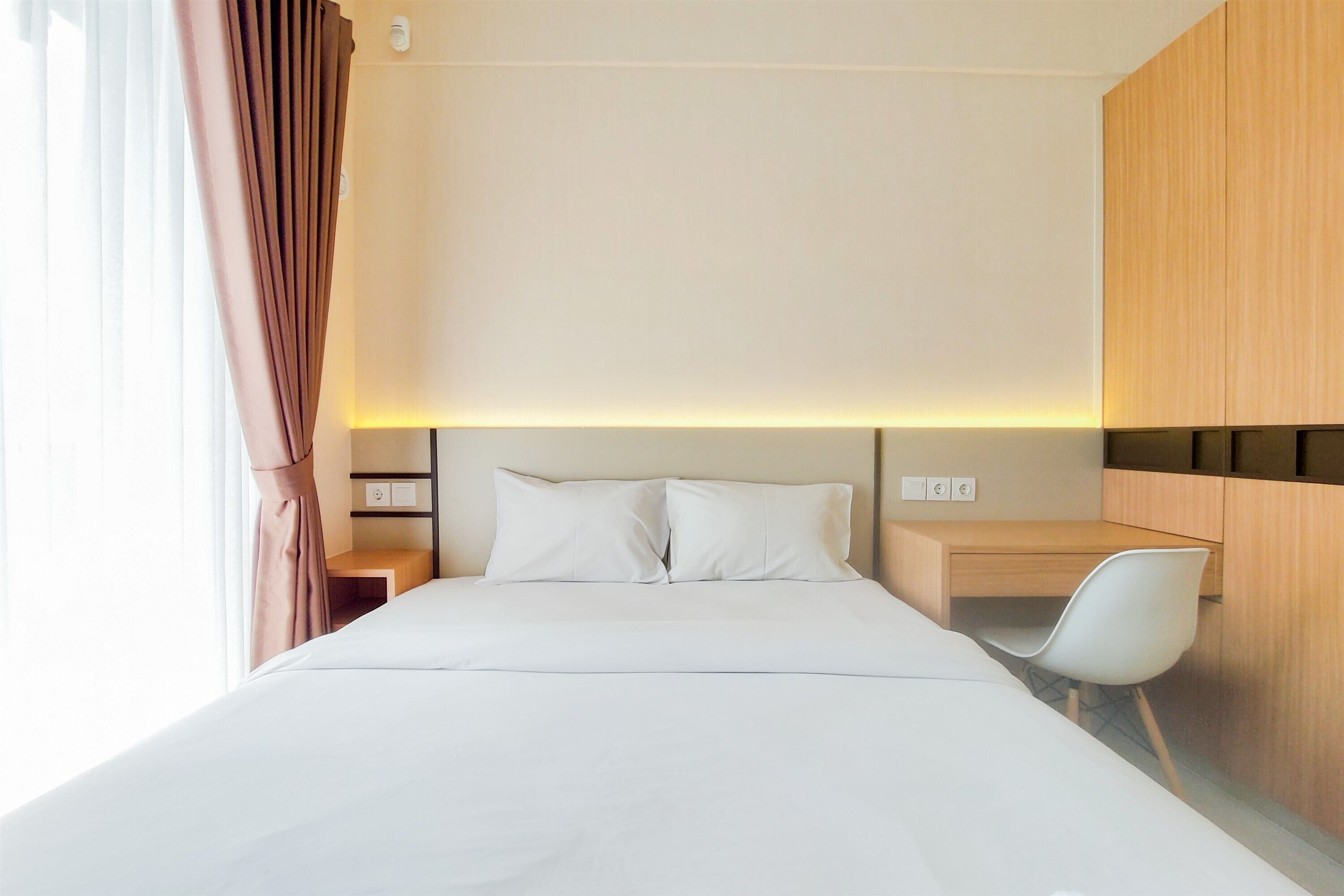 A hotel room with a large bed, a desk, and a chair.