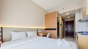 A hotel room with a bed, a desk, and a kitchenette. - Well Design And Comfy Studio Sky House Bsd Apartment (Pagedangan)