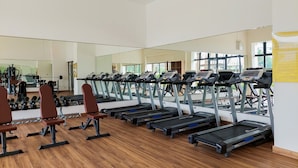 A gym with treadmills, weight benches, and a large mirror. - Well Design And Comfy Studio Sky House Bsd Apartment (Pagedangan)