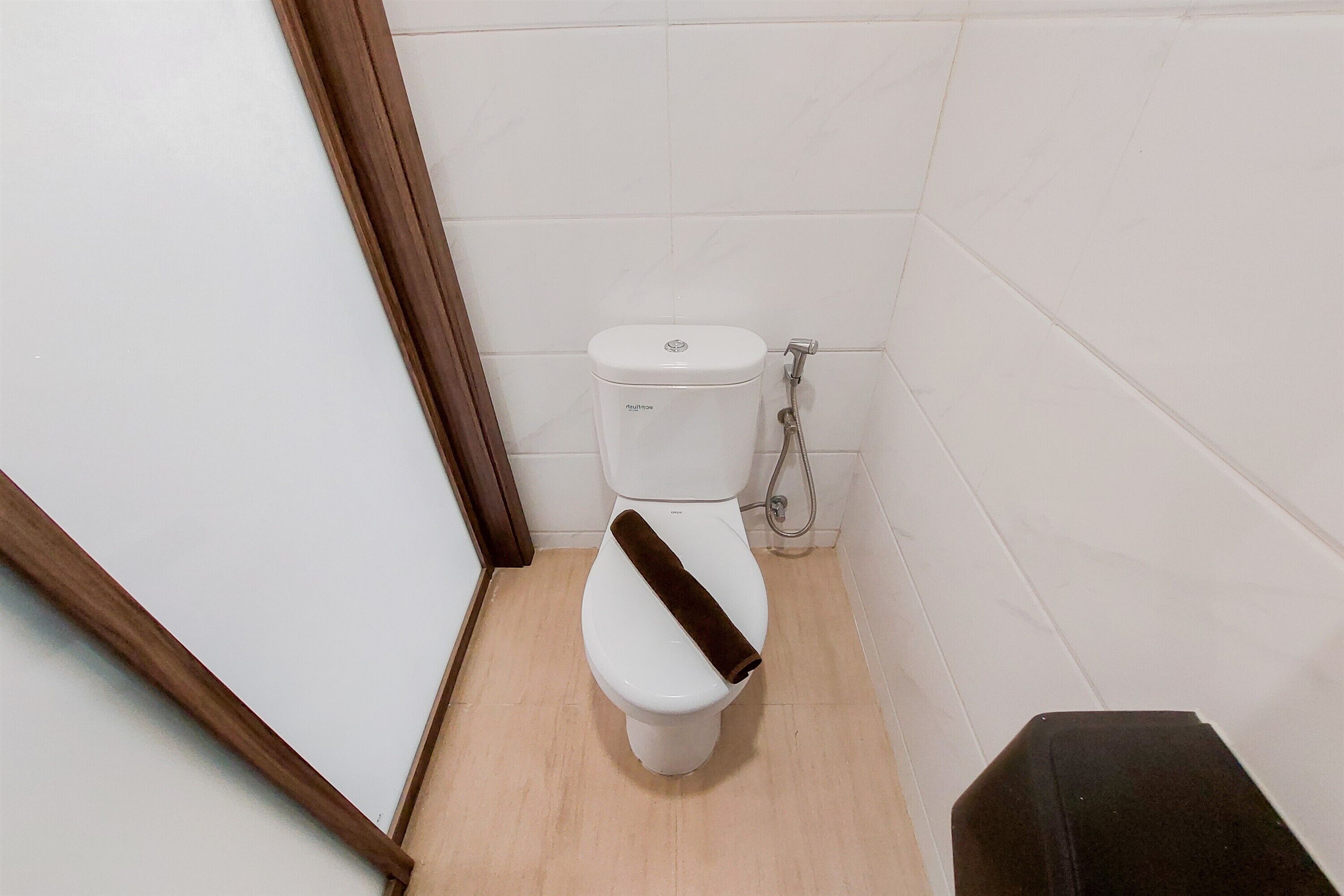 A small, clean bathroom with a white toilet, a shower, and a wooden door frame.