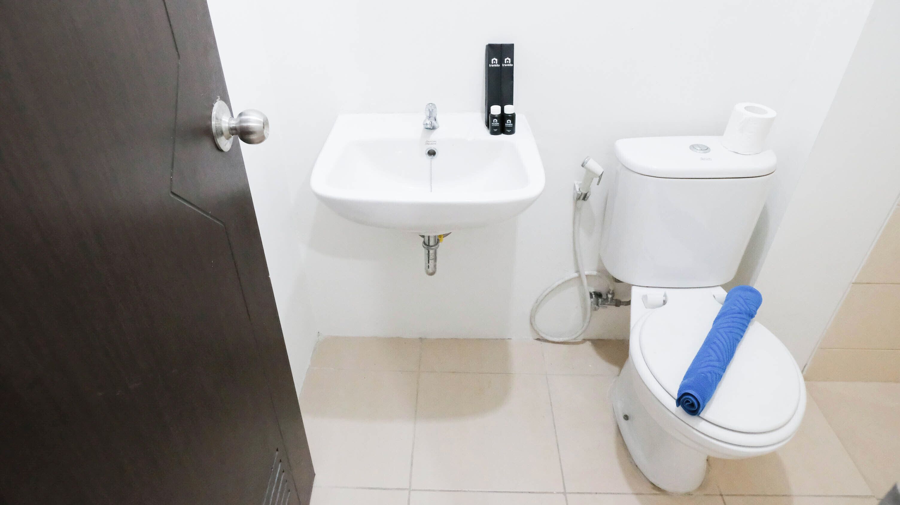 A bathroom with a white sink, toilet, and a towel on the toilet seat.