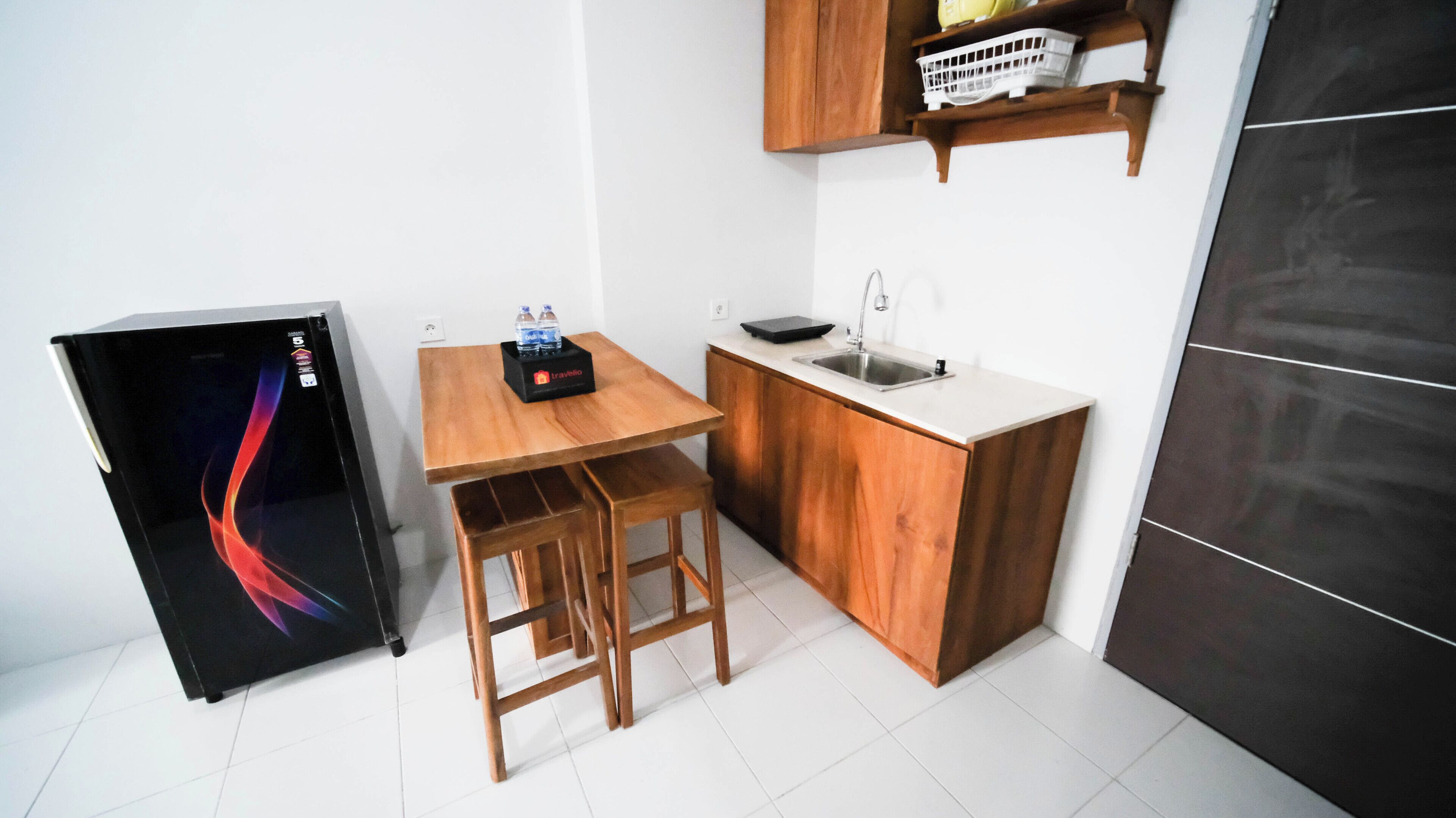 A compact kitchen with a wooden table, a sink, and a refrigerator.