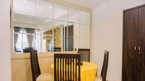 A dining area with a round table, four chairs, and a large mirror on the wall. - Nice 2Br At Branz Bsd City Apartment (Pagedangan)