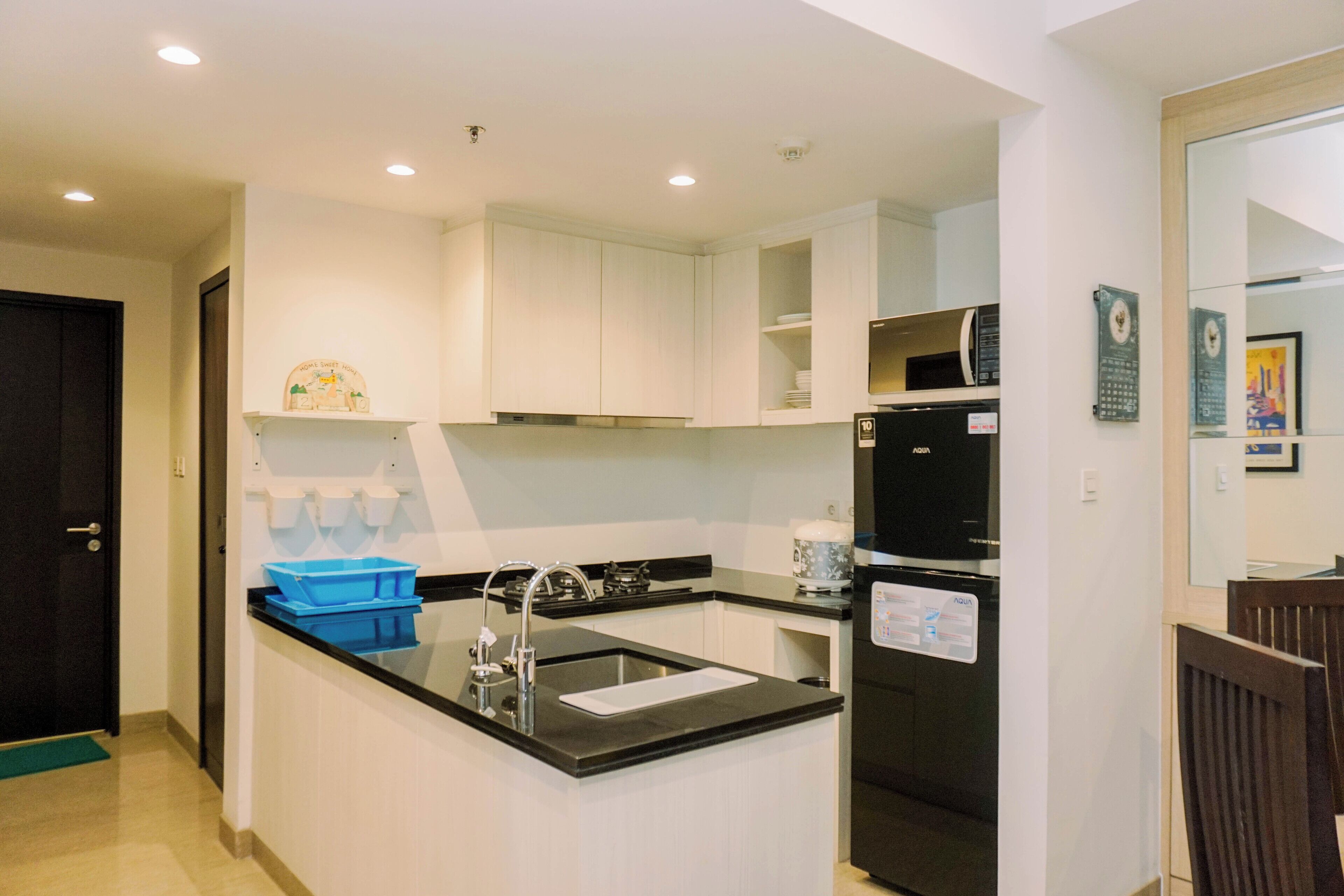 A modern kitchen with white cabinets, a black refrigerator, and a blue storage bin.