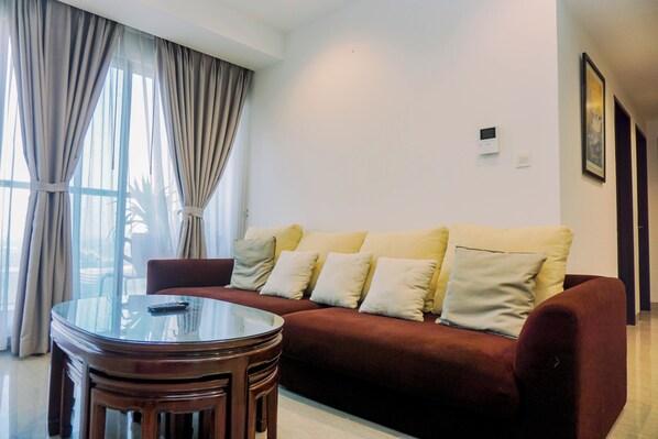 A living room with a red sofa, a glass coffee table, and a chair. - Nice 2Br At Branz Bsd City Apartment (Pagedangan)