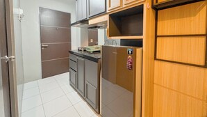 Eine kompakte Küche mit Holzausstattung, einem Edelstahlkühlschrank und einem Einbauofen.
