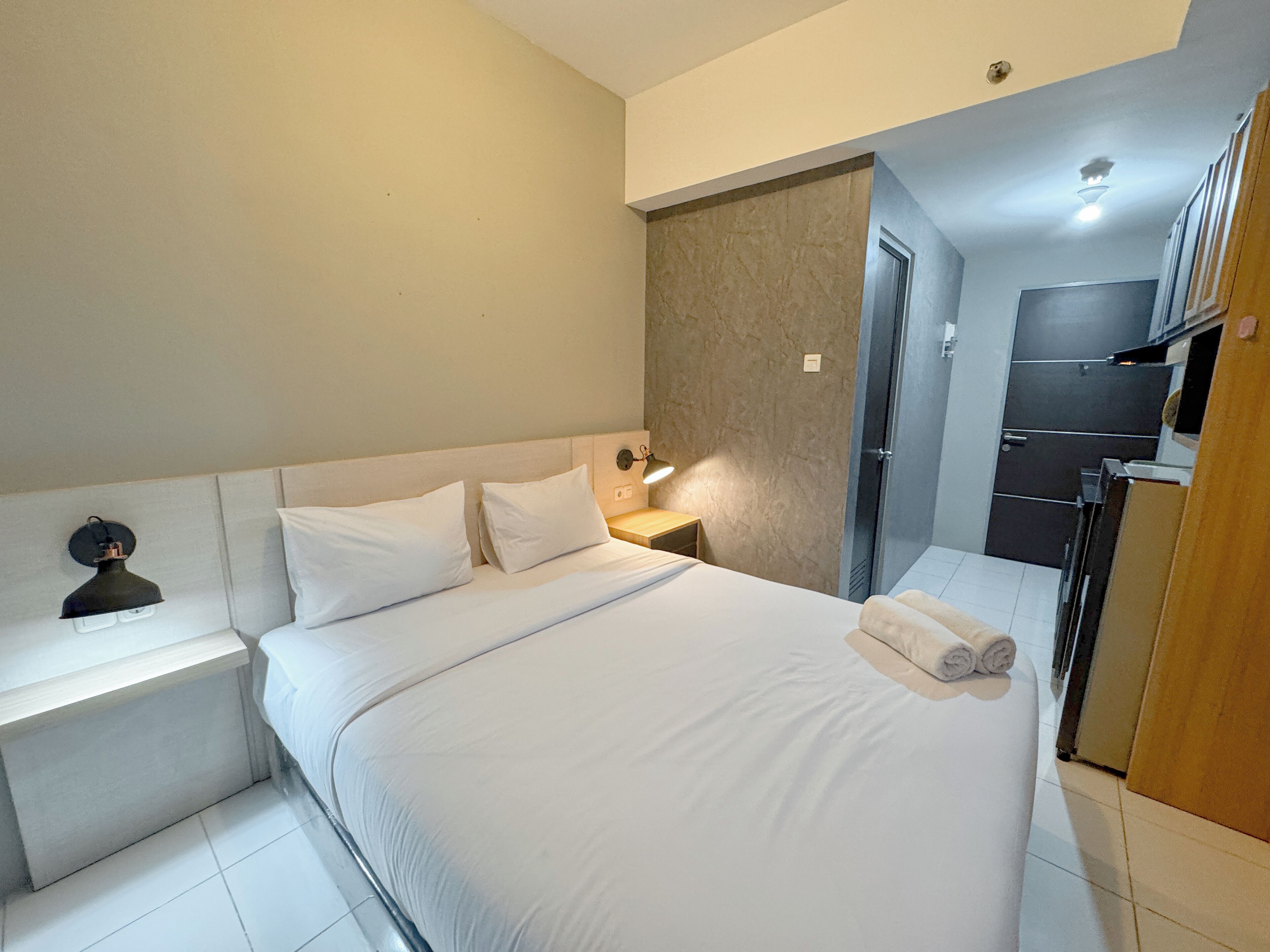A hotel room with a bed, a bedside table, a lamp, and a wardrobe.