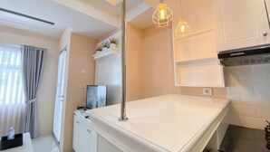 Una cocina moderna con armarios blancos, una campana extractora de acero inoxidable e iluminación colgante.