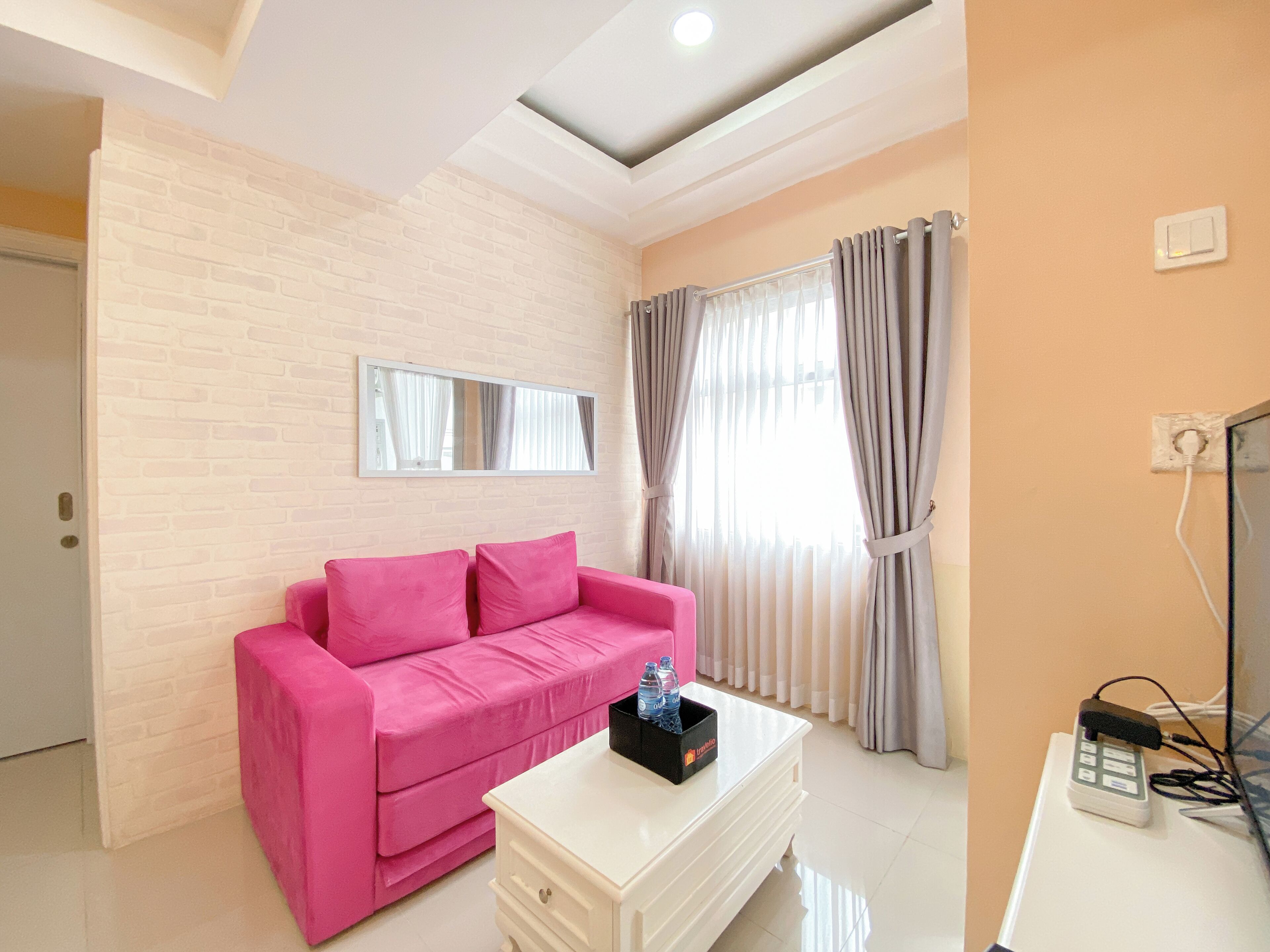 A modern living room with a pink sofa, a white coffee table, and a large window with curtains.