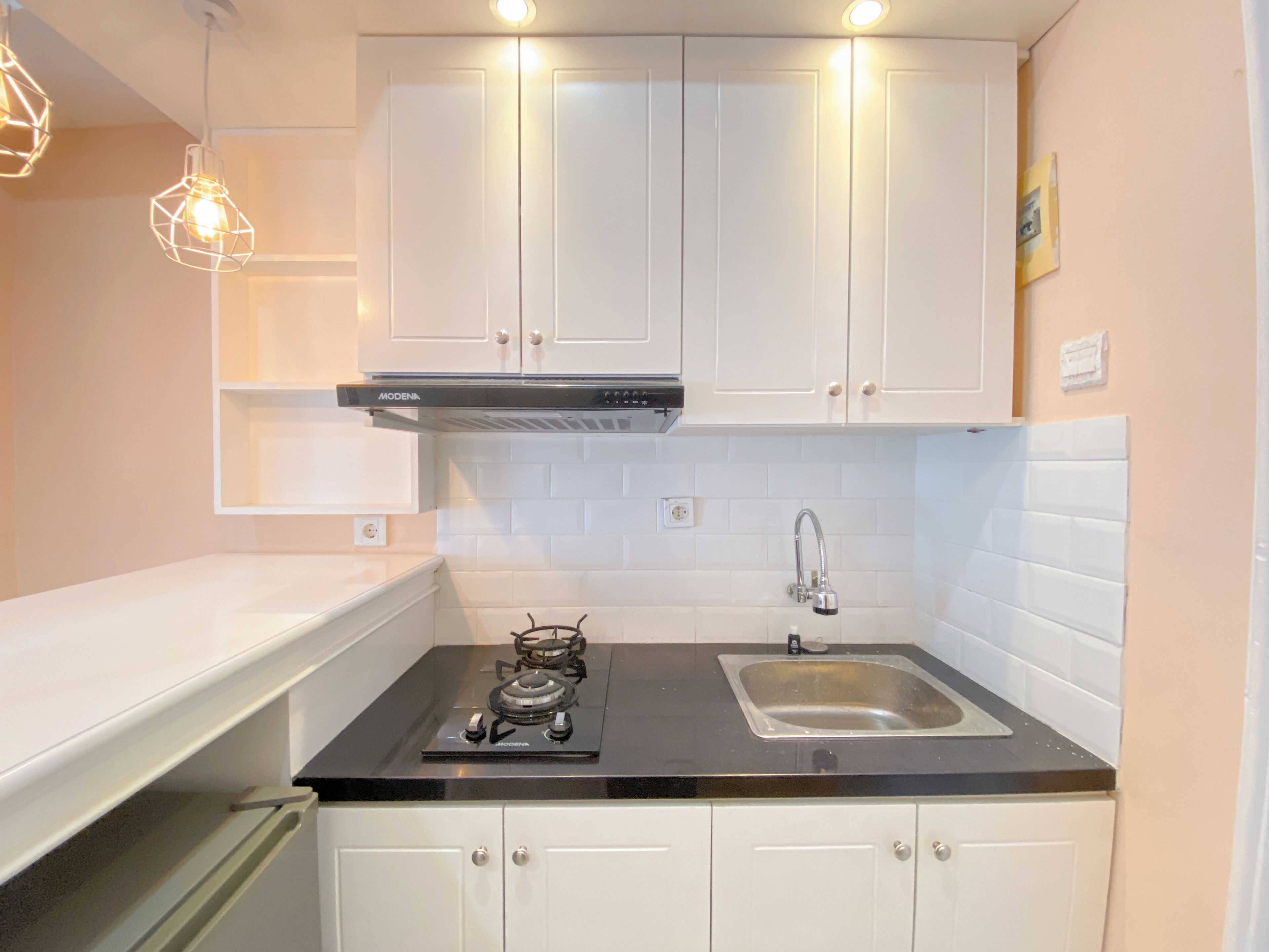 A modern kitchen with white cabinets, a black countertop, a gas stove, a sink, and pendant lighting.