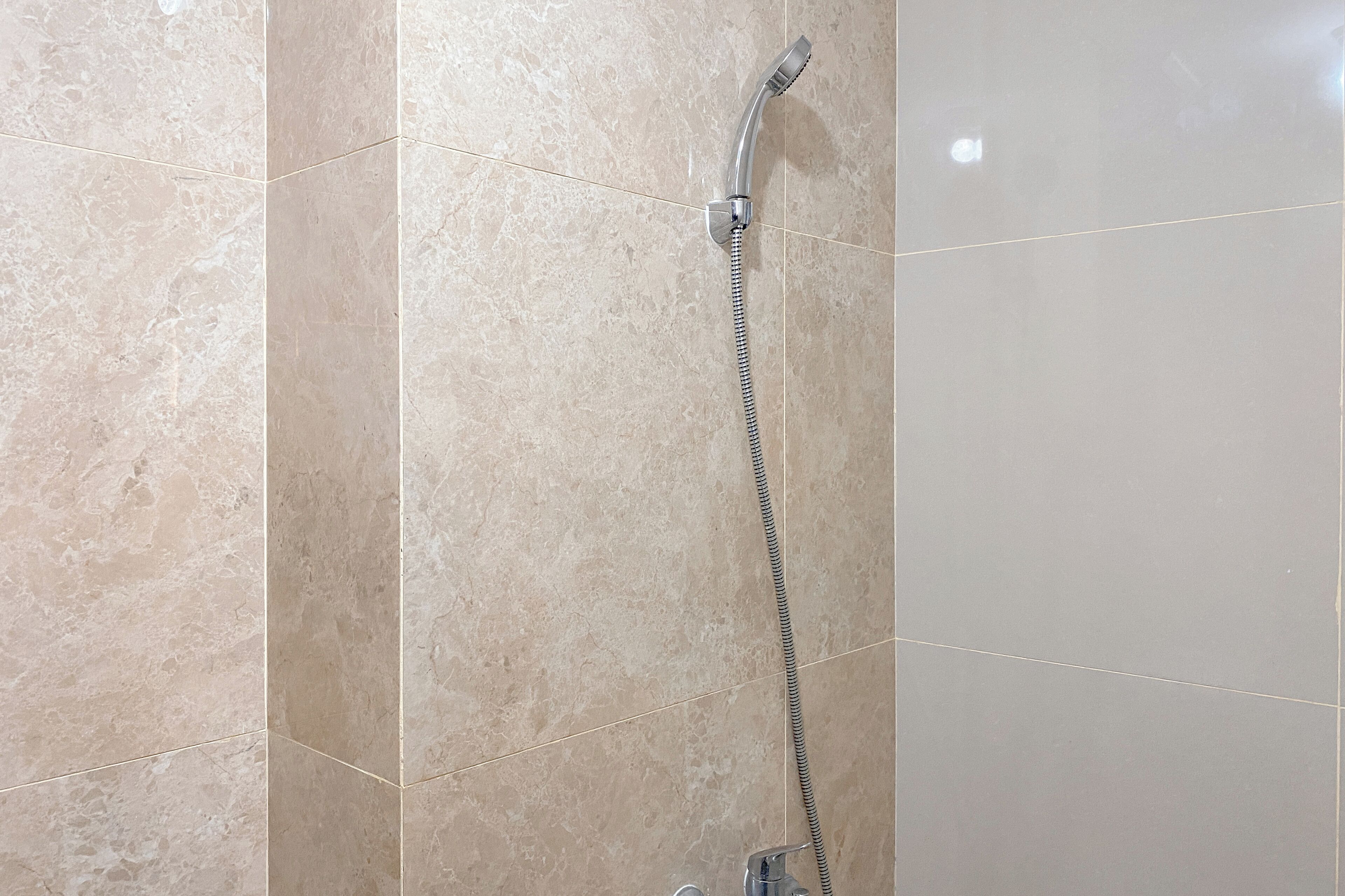 Een douche met een handdouche en een flexibele slang.