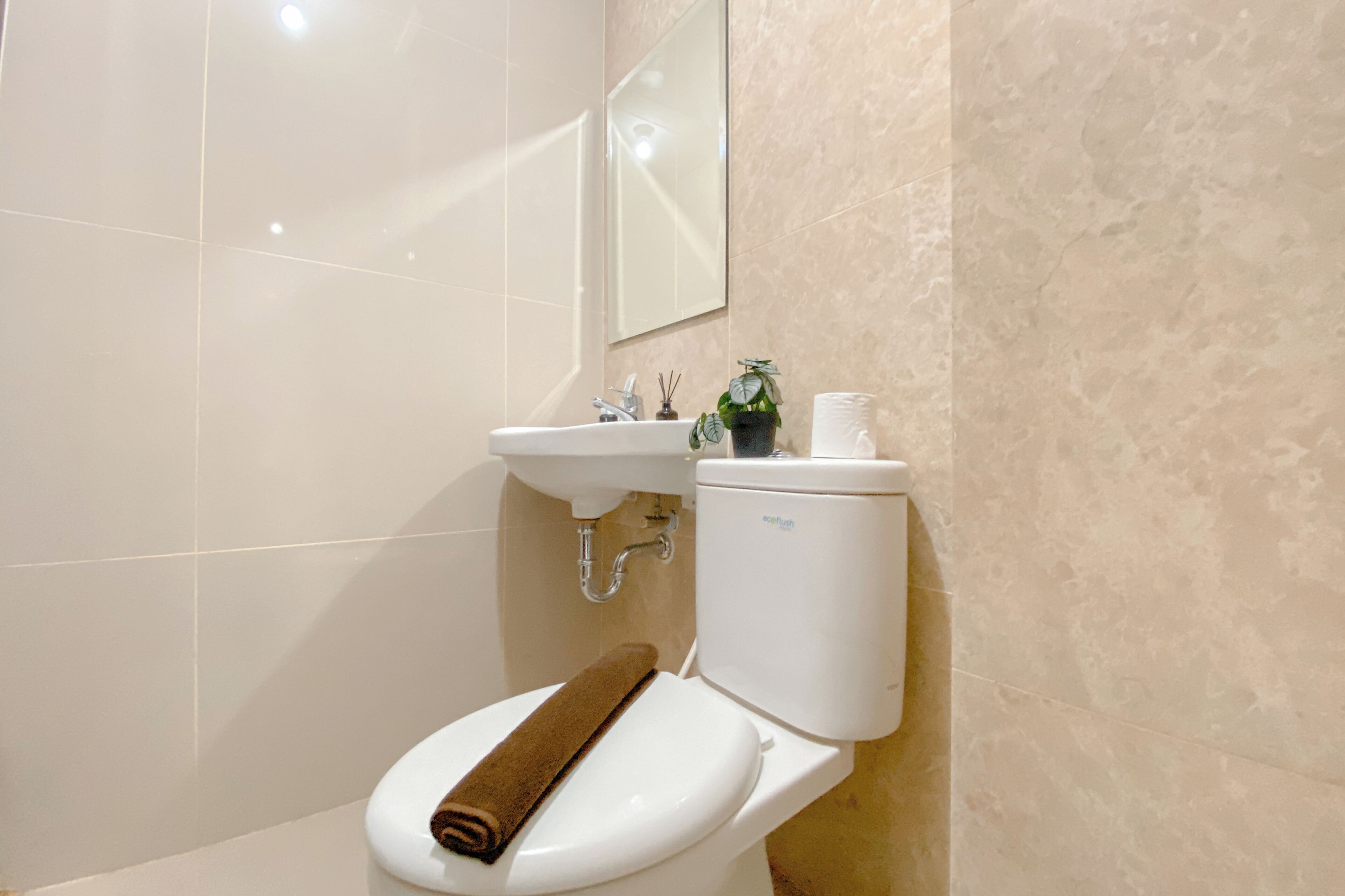 Une salle de bain avec des toilettes blanches, un lavabo et un miroir.