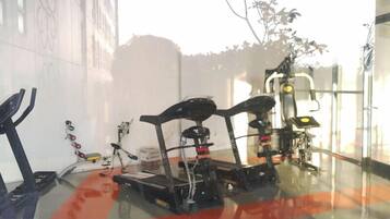 A gym with exercise equipment, including treadmills and weight machines, in a room with large windows.