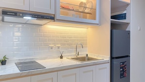 A modern kitchen with white cabinetry, a stainless steel sink, a built-in oven, and a refrigerator with a digital display. - Comfortable 1Br Apartment At Pollux Chadstone (Cikarang)