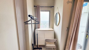 A small, compact room with a window, a chair, a radiator, and a coat rack. - Good Place And Tidy Studio At Tamansari Prospero Apartment (Sidoarjo)