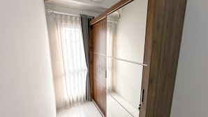 Een kamer met een schuifdeur, een raam met dunne gordijnen en een betegelde vloer.