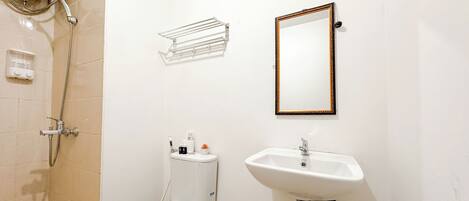 Une salle de bain comprenant des toilettes, un lavabo, une douche et un miroir.