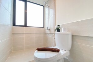 Un baño con inodoro, ducha y ventana.