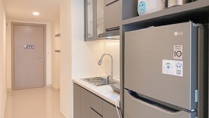 A modern kitchen with a stainless steel refrigerator, a built-in oven, and a sink with a faucet. - Cozy And Modern 2Br At Meikarta Apartment (Cikarang)