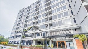 A multi-story hotel with a modern architectural design, featuring a prominent entrance with a glass door and a covered waiting area. - Elegant And Spacious 2Br Loft Green Park Yogyakarta Apartment (Depok)