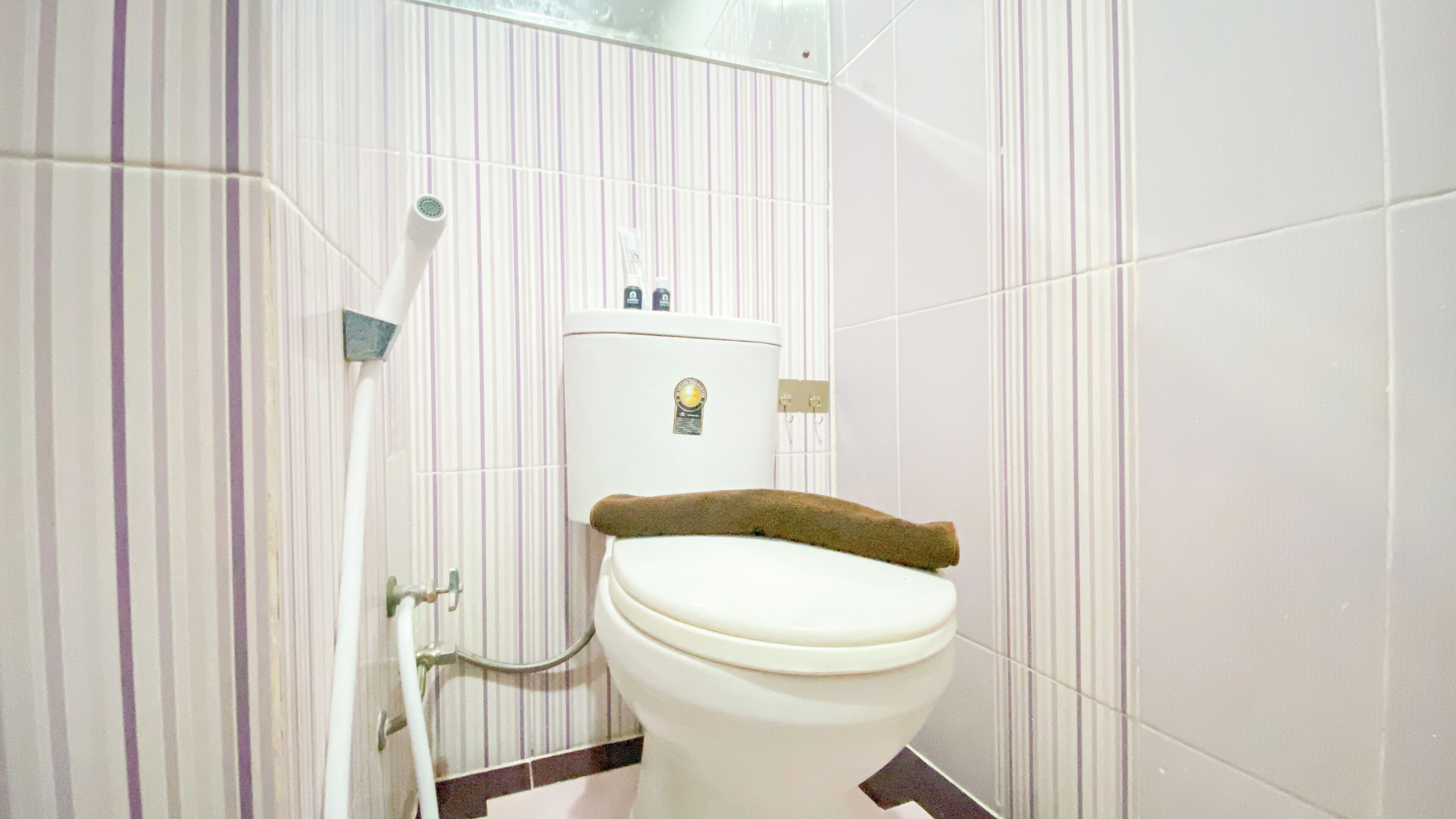 A bathroom with a toilet, a shower, and a hand dryer.