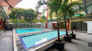 A swimming pool with two lanes, surrounded by potted palm trees and outdoor seating. - Good And Homey 1Br Apartment Mt Haryono Residence (Jakarta)