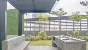An outdoor patio area with a concrete floor, two concrete sinks, a wooden bench, and a green artificial grass area. - Homey And Compact 2Br Podomoro City Deli Medan Apartment (Medan)