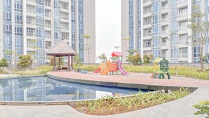 A residential area with a children's play area, a small pavilion, and a swimming pool. - Homey And Compact 2Br Podomoro City Deli Medan Apartment (Medan)