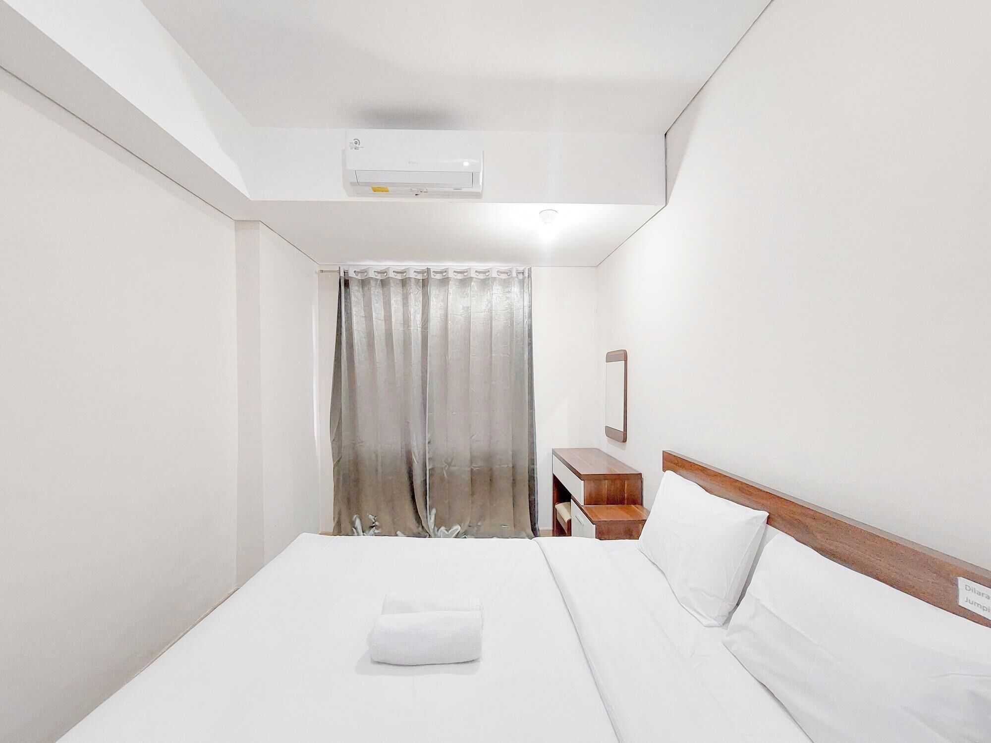A hotel room with a bed, a nightstand, a mirror, and a window with curtains.