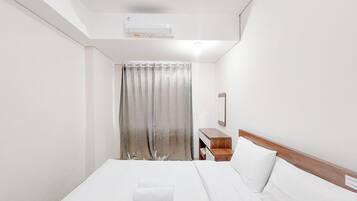 A hotel room with a bed, a nightstand, a mirror, and a window with curtains.