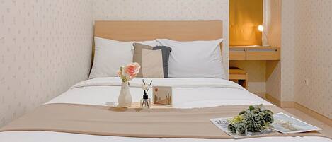 A neatly made bed with a wooden headboard, a bedside table with a lamp, and a small decorative item on the nightstand.