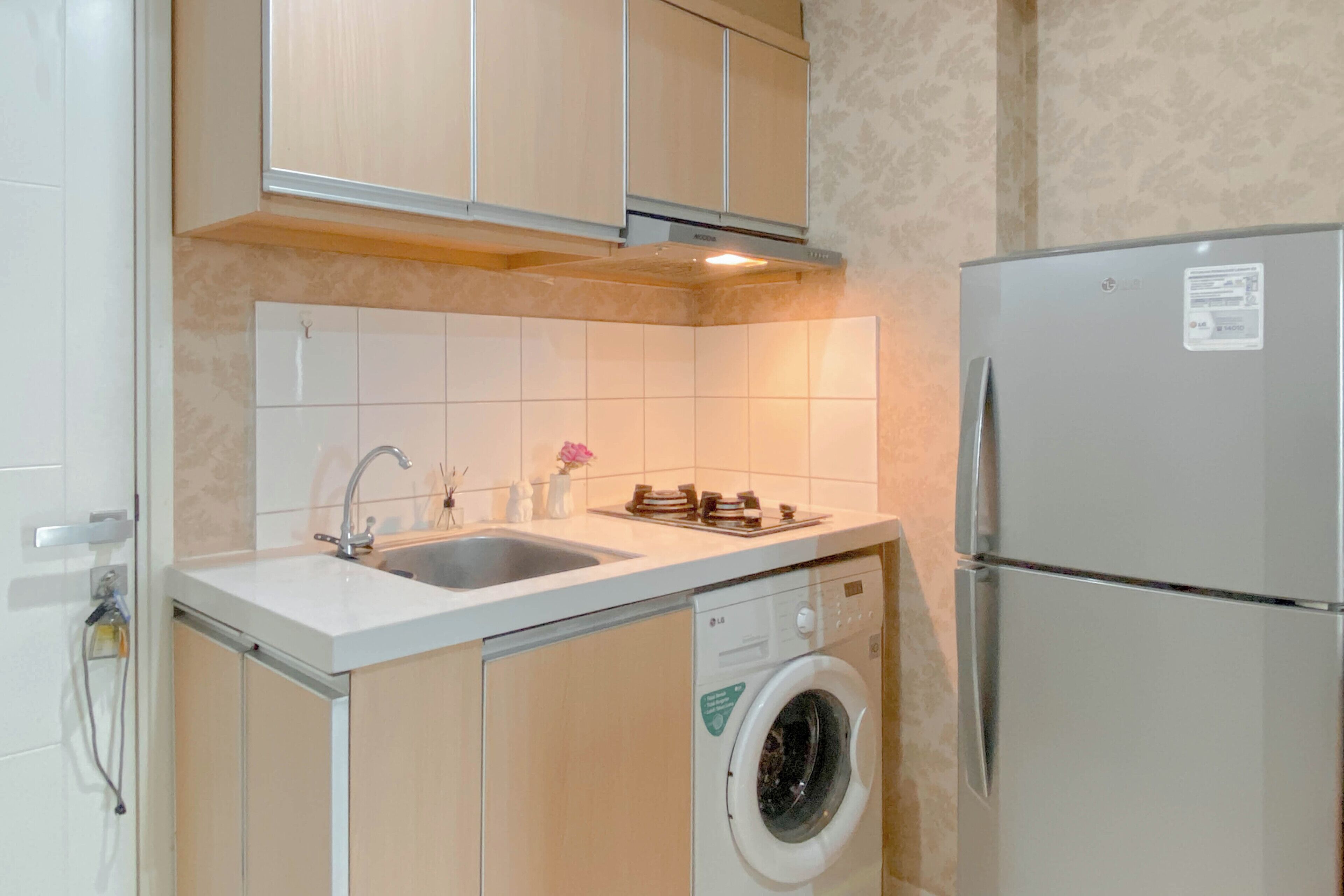 A compact kitchen with a built-in washing machine, a refrigerator, and a sink with a faucet.
